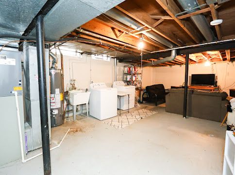 basement with water heater, washer and dryer, and sink