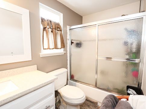 full bathroom with toilet, vanity, and shower / bath combination with glass door