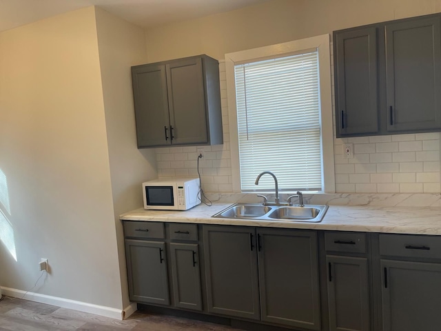 kitchen featuring backsplash, gray cabinets, sink, and hardwood / wood-style floors