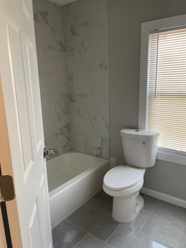 bathroom with tile patterned flooring, toilet, and tiled shower / bath