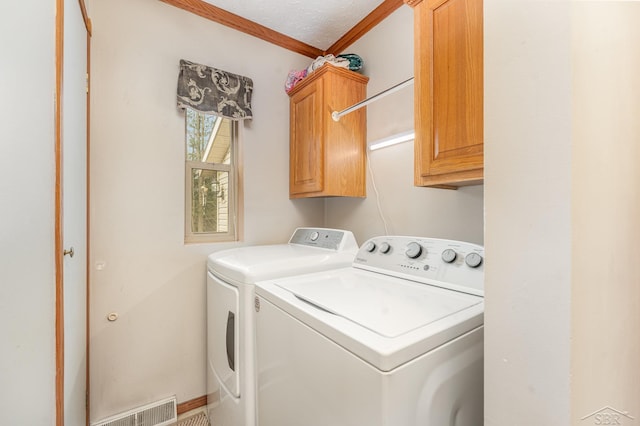 laundry area with cabinets, ornamental molding, a textured ceiling, and washing machine and dryer