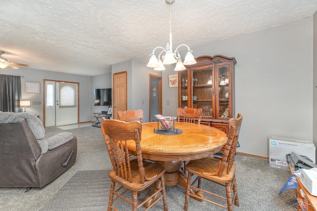 dining space featuring carpet, ceiling fan with notable chandelier, and a textured ceiling