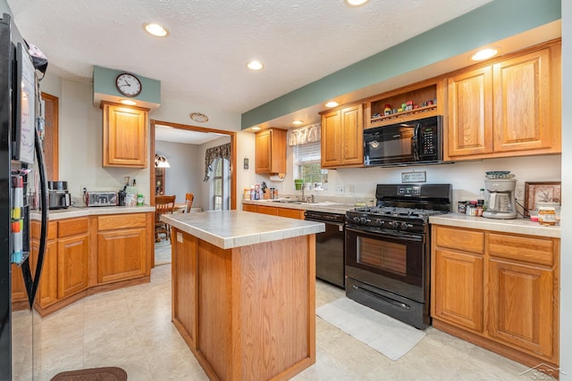 kitchen featuring black appliances, a kitchen island, sink, and a textured ceiling