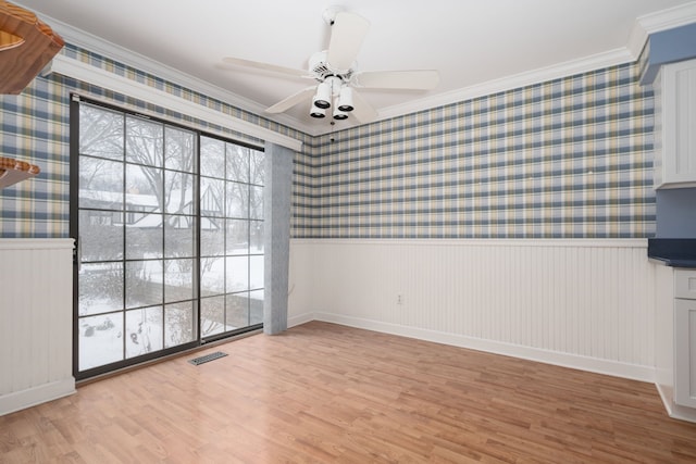 empty room with ceiling fan, ornamental molding, and light wood-type flooring