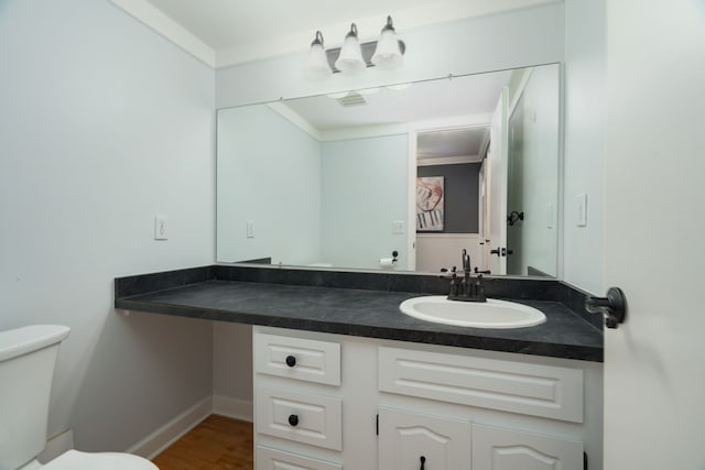 bathroom featuring toilet, crown molding, hardwood / wood-style flooring, and vanity