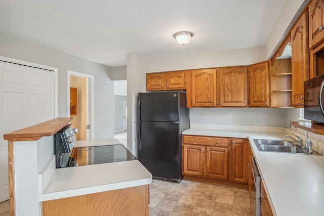 kitchen featuring stainless steel stove, black fridge, and sink