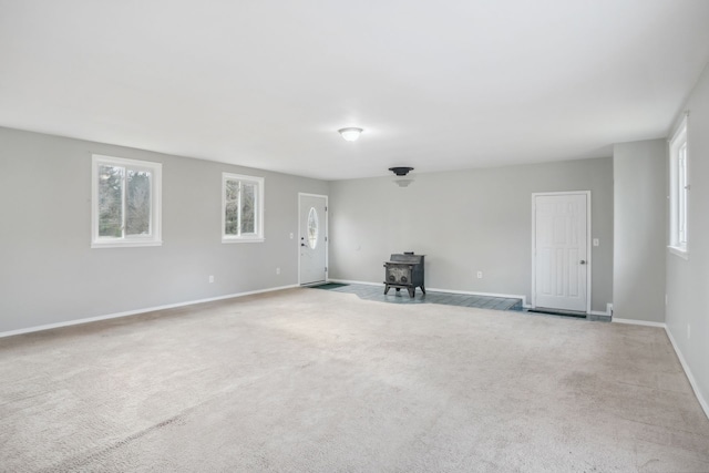 unfurnished living room featuring a wood stove and light carpet