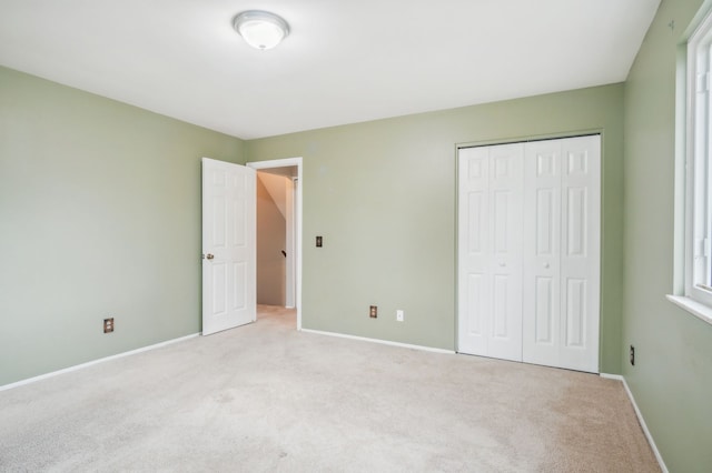 unfurnished bedroom featuring light carpet and a closet