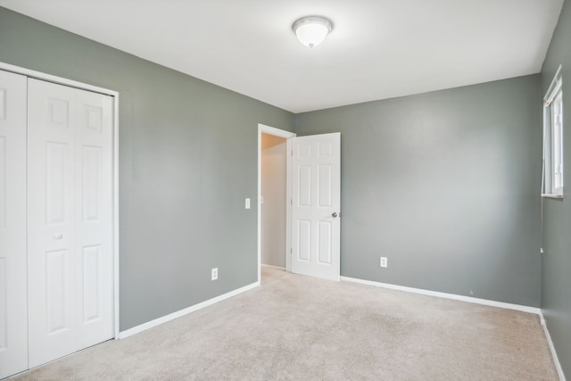 unfurnished bedroom with light colored carpet and a closet