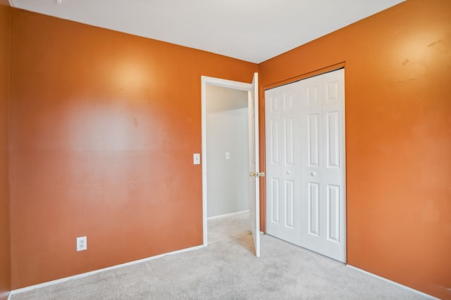 unfurnished bedroom featuring light carpet and a closet