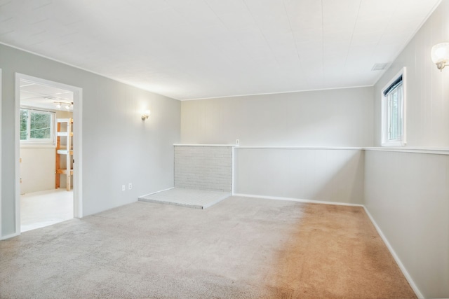 spare room with a fireplace, light colored carpet, and a wealth of natural light