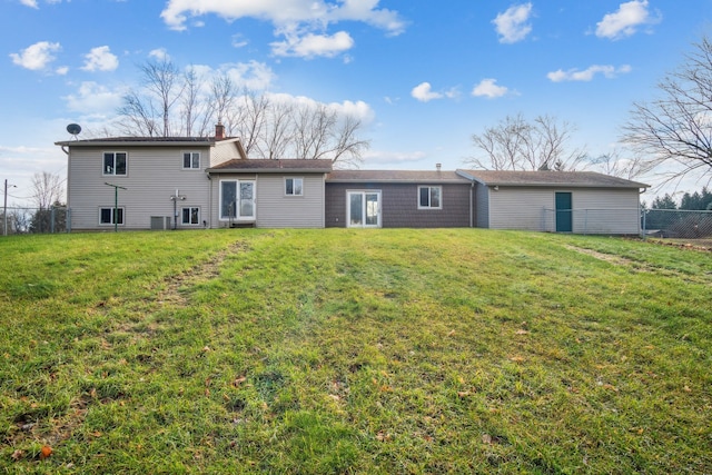 rear view of property with central air condition unit and a yard