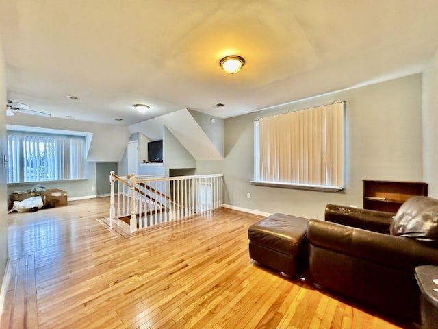 living room featuring light hardwood / wood-style floors, vaulted ceiling, and ceiling fan