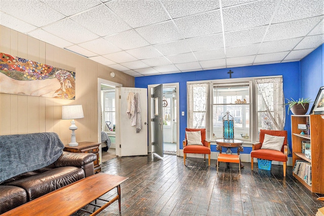 living room featuring dark wood-type flooring and a paneled ceiling