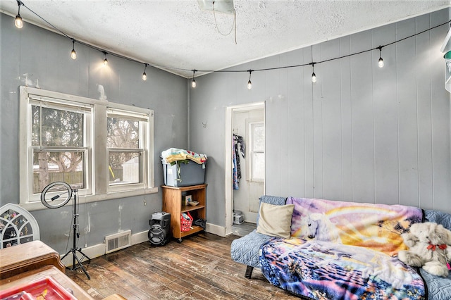 bedroom featuring multiple windows, dark hardwood / wood-style floors, and a textured ceiling