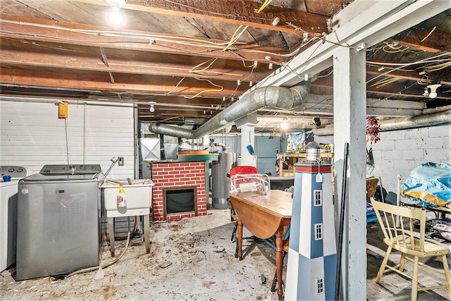 basement featuring washer and dryer, sink, water heater, and a brick fireplace