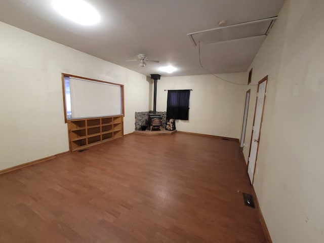 basement with dark hardwood / wood-style flooring, a wood stove, and ceiling fan