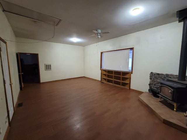 unfurnished living room featuring a wood stove, ceiling fan, and hardwood / wood-style floors