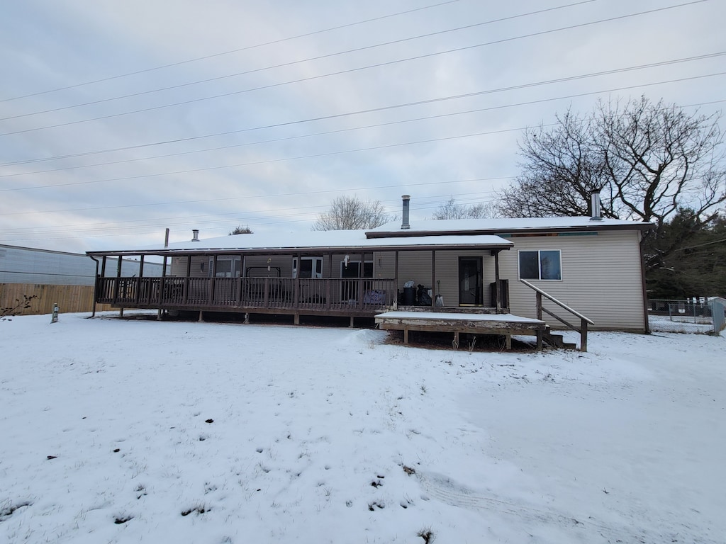 snow covered rear of property featuring a deck