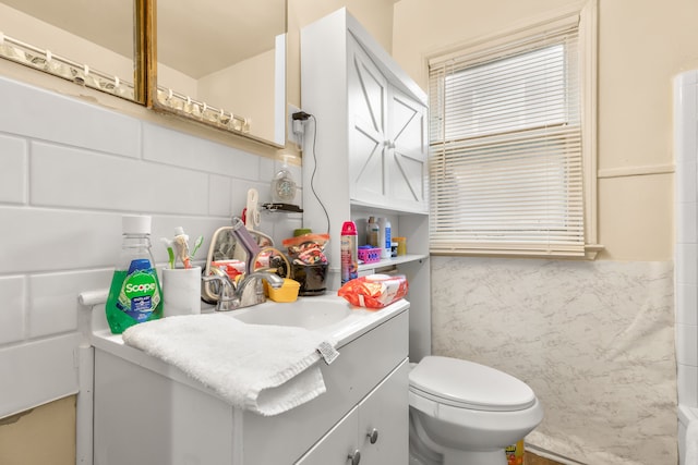 bathroom with vanity, tile walls, and toilet