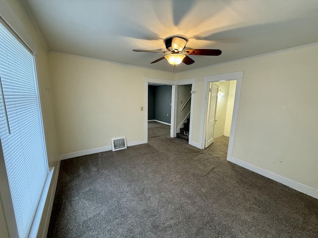 unfurnished bedroom with ceiling fan and dark colored carpet