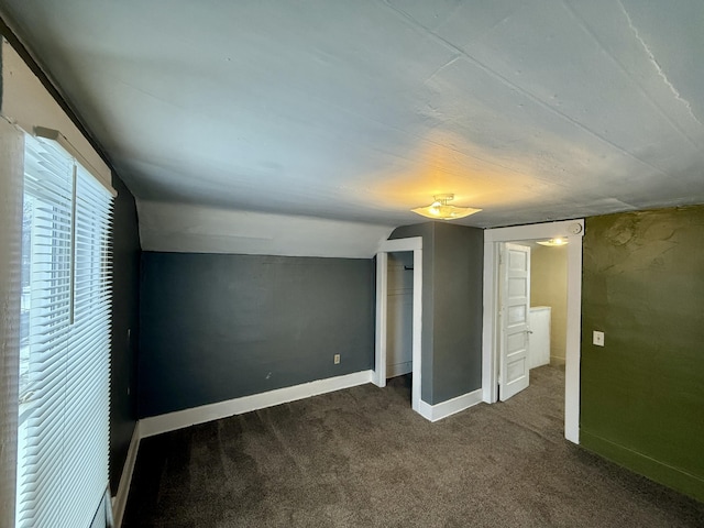 unfurnished bedroom featuring dark colored carpet and vaulted ceiling