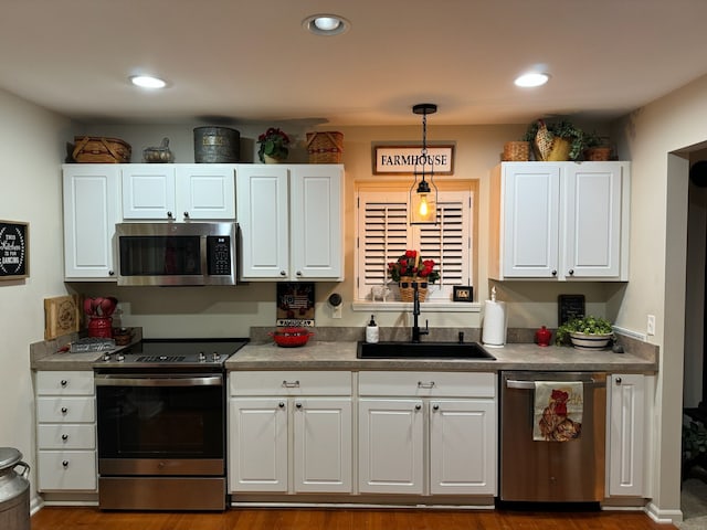 kitchen with stainless steel appliances, white cabinets, decorative light fixtures, and sink