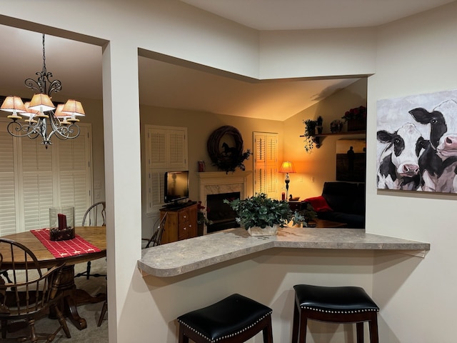 kitchen featuring decorative light fixtures, a fireplace, kitchen peninsula, a kitchen bar, and a chandelier