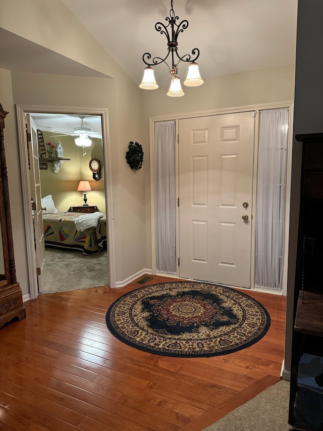 foyer entrance featuring vaulted ceiling, an inviting chandelier, and hardwood / wood-style flooring