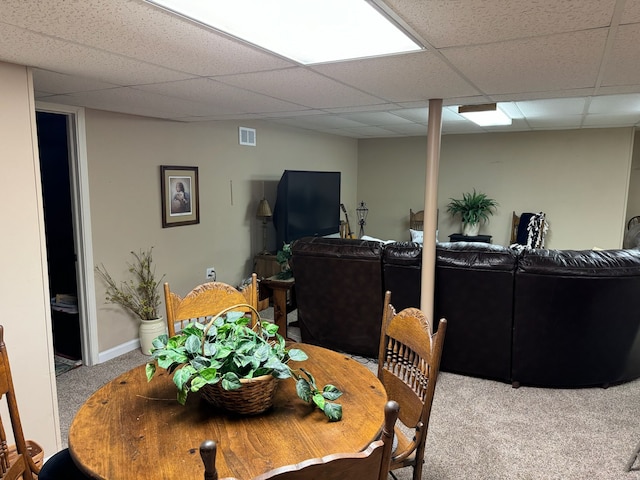 carpeted dining area featuring a drop ceiling