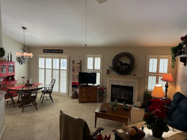 living room with light colored carpet, a high end fireplace, a healthy amount of sunlight, and a notable chandelier