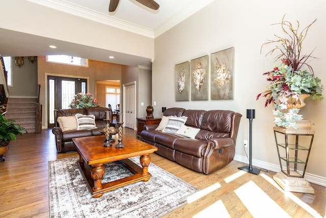 living room with a towering ceiling, hardwood / wood-style floors, crown molding, and ceiling fan