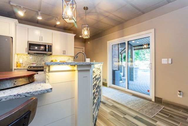 kitchen with backsplash, white cabinets, stainless steel appliances, and pendant lighting