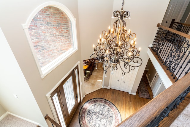 foyer with a notable chandelier, a towering ceiling, and hardwood / wood-style floors