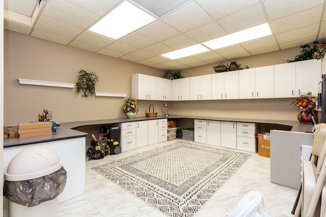 kitchen with a drop ceiling, white cabinetry, and built in desk