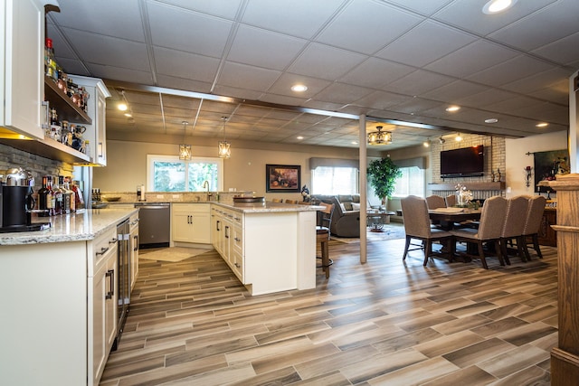 kitchen with a kitchen breakfast bar, kitchen peninsula, pendant lighting, and white cabinets