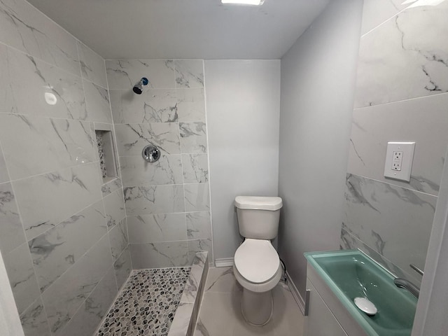 bathroom featuring tiled shower, toilet, and sink