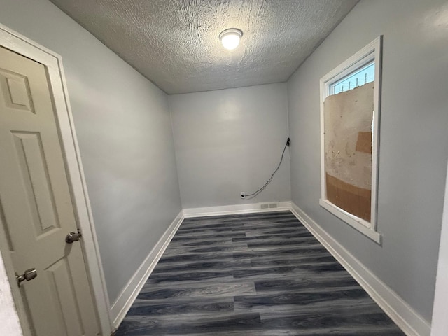 empty room with a textured ceiling and dark hardwood / wood-style floors