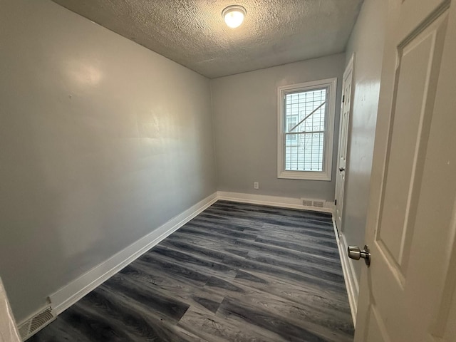 empty room featuring dark wood-type flooring and a textured ceiling