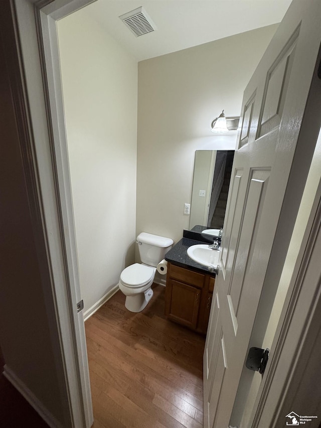 bathroom with vanity, toilet, and wood-type flooring