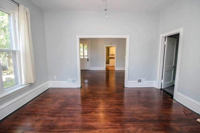 unfurnished room featuring dark hardwood / wood-style flooring and a healthy amount of sunlight