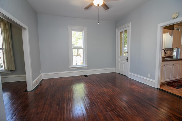 spare room with ceiling fan, sink, and dark wood-type flooring