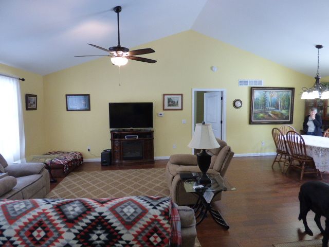 living room featuring ceiling fan with notable chandelier, lofted ceiling, and hardwood / wood-style flooring