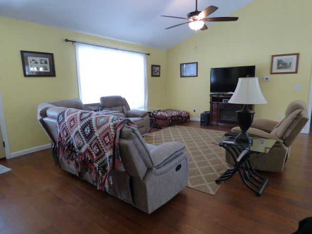 living room with hardwood / wood-style floors, vaulted ceiling, and ceiling fan