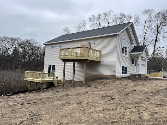 rear view of house featuring a deck and roof with shingles