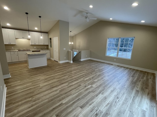 kitchen with a ceiling fan, a kitchen island, open floor plan, wood finished floors, and white cabinetry