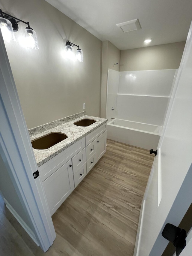 bathroom featuring a sink, bathing tub / shower combination, and wood finished floors