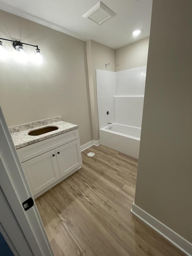 full bath featuring bathtub / shower combination, baseboards, wood finished floors, and vanity