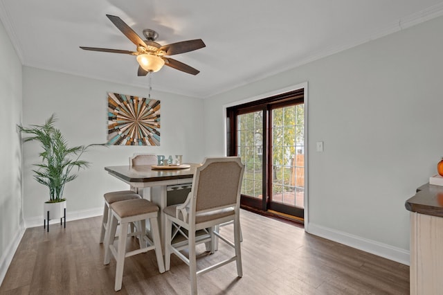 dining room with ceiling fan, ornamental molding, and dark wood-type flooring