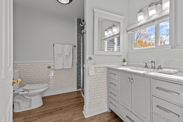 bathroom with hardwood / wood-style flooring, vanity, toilet, and tile walls